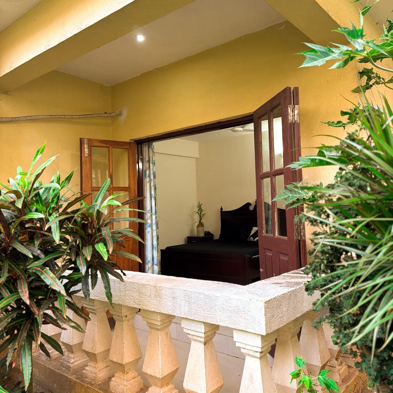 Balcony with potted palms and a white balustrade outside the main bedroom's double doors