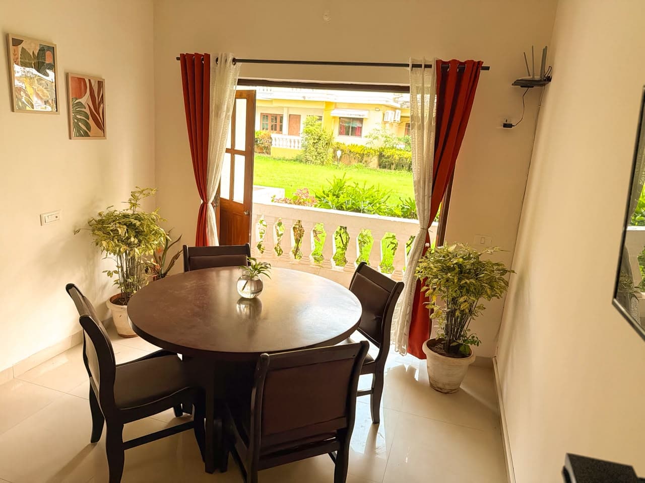 Round dining table for four beside open balcony doors and a green lawn