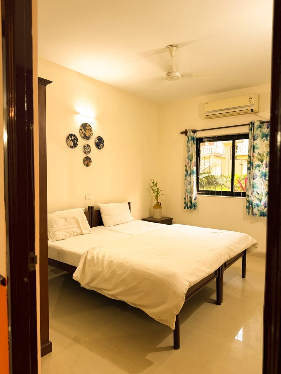 Second bedroom seen through the doorway, with a ceiling fan and a window onto the garden