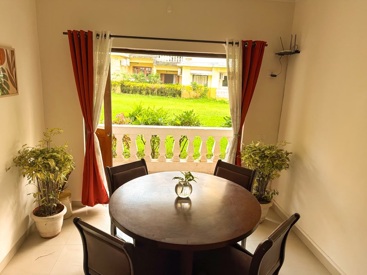 Dining table framed by red and cream curtains, looking out over the balcony to the garden
